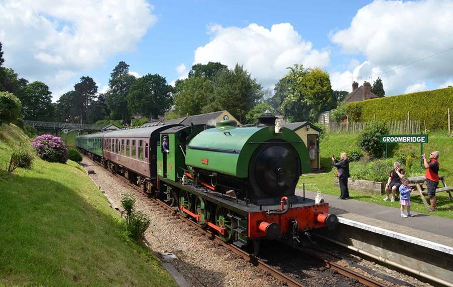 Steam train in countryside approaching station platform